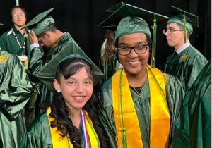 Two graduates wear robe and cap during NOVA graduation.