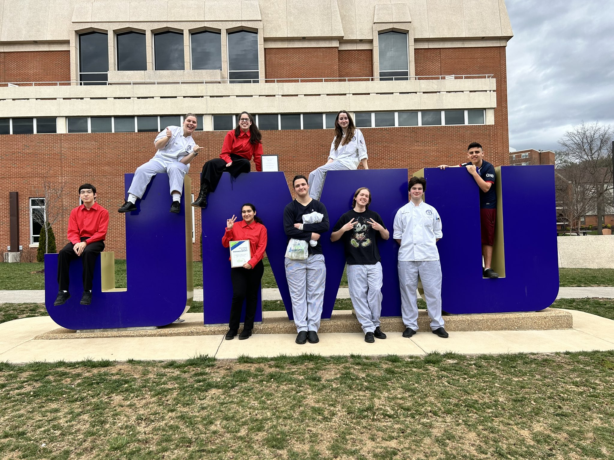 Picture of ACC Culinary Arts students at the VA ProStart Culinary Arts Competition (students are seated or standing near the 3D JMU letters on campus)