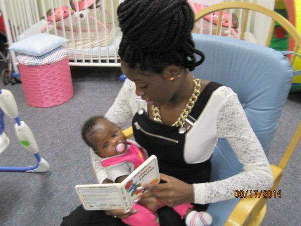 ACC-Student liest einem Säugling vor